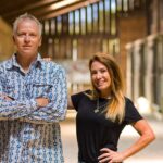 Simon and Caprice Arkell pose for a portrait inside a horse barn