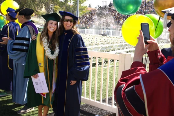 Gabrielle Gutierrez poses for a photo with a faculty member at commencement