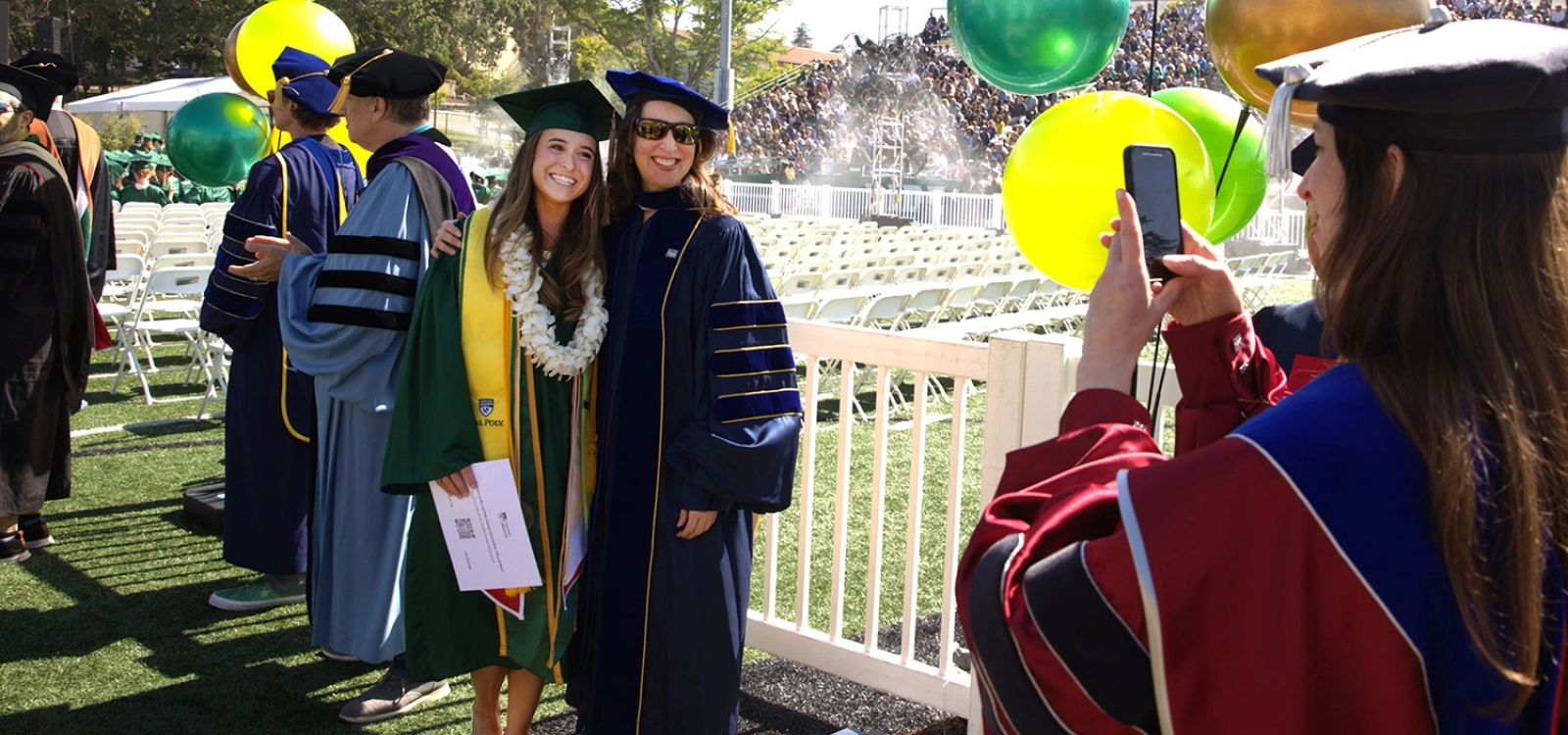 Gabrielle Gutierrez poses for a photo with a faculty member at commencement