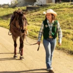 A rodeo member walks her horse down a trail