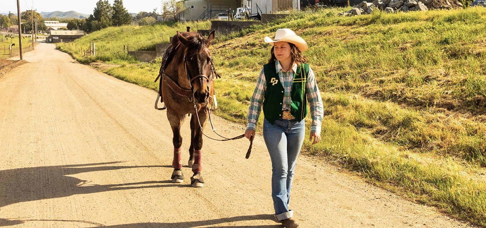A rodeo member walks her horse down a trail